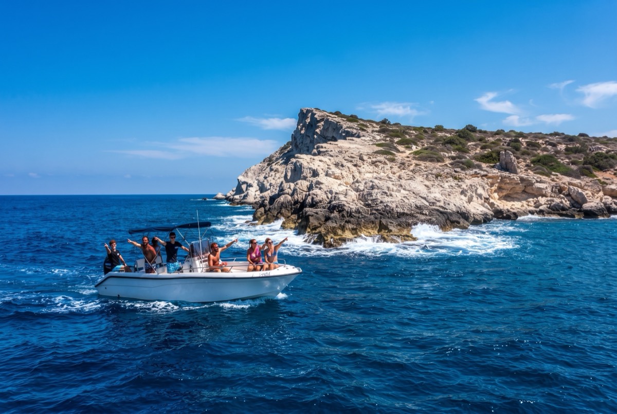 The rocky tip of the Akamas at Cape Arnaoutis with a speedboat passing the point