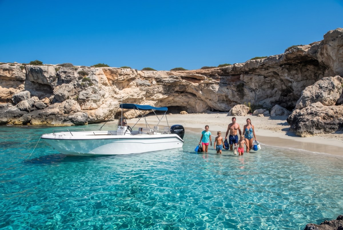 Small empty beach under the Akamas cliffs with a speedboat anchored just offshore