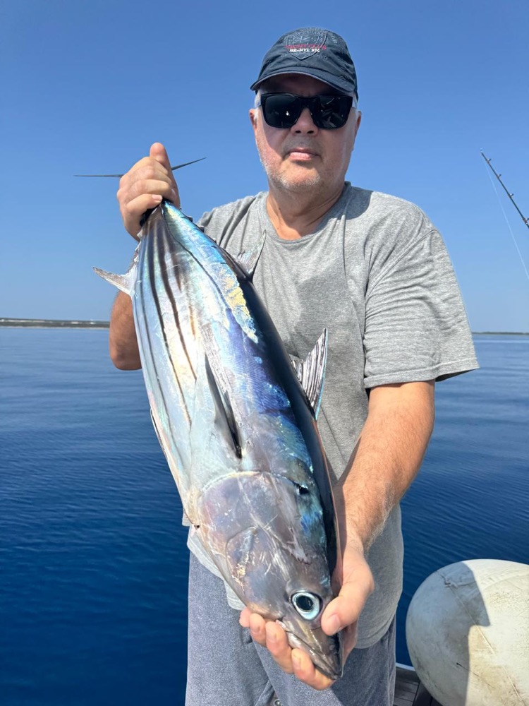 Guest holding a large fish on the deck of the yacht Sunny Day