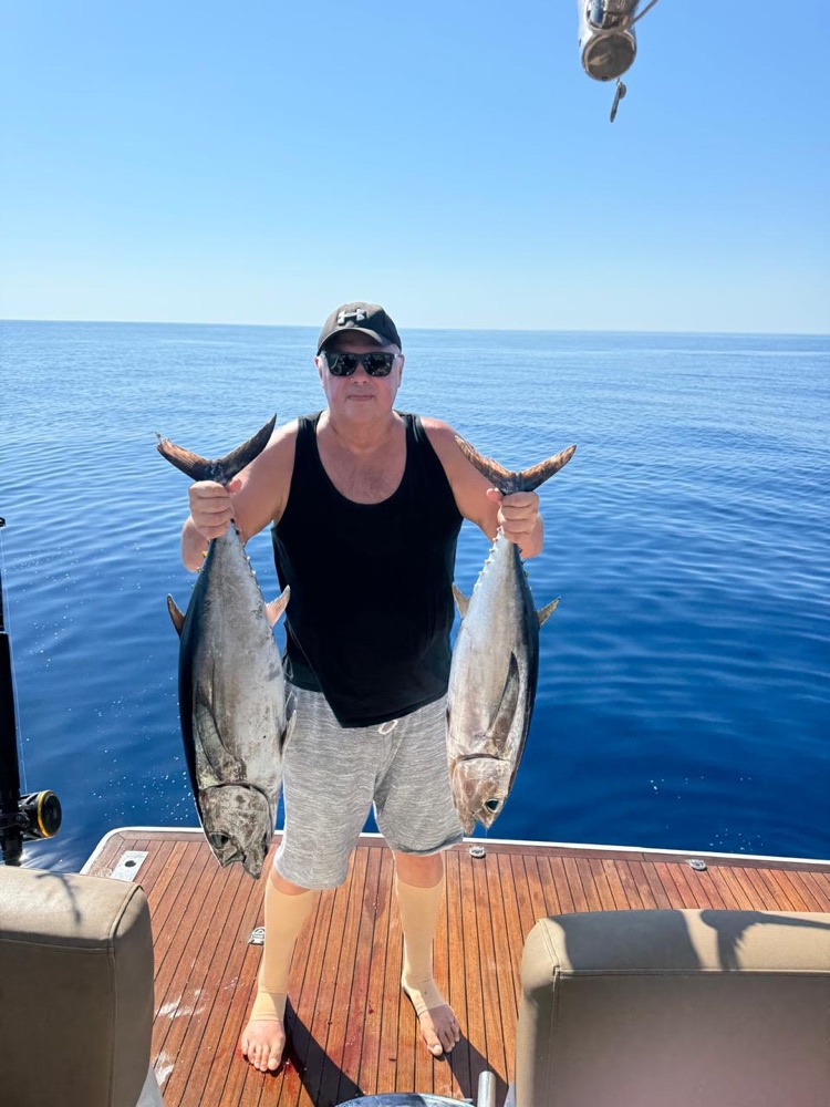 Guest holding two fish on the yacht Sunny Day