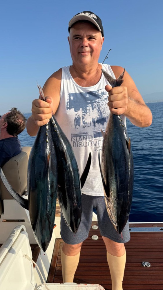 Guest with two fish on the stern deck of the yacht