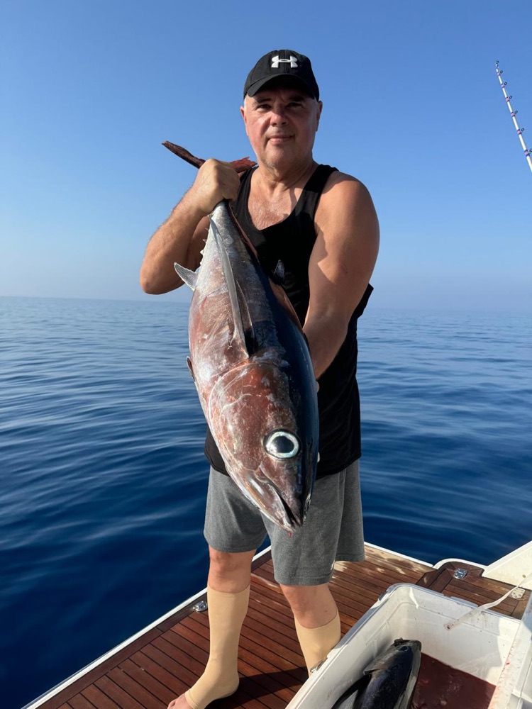 Guest holding two fish on the yacht deck