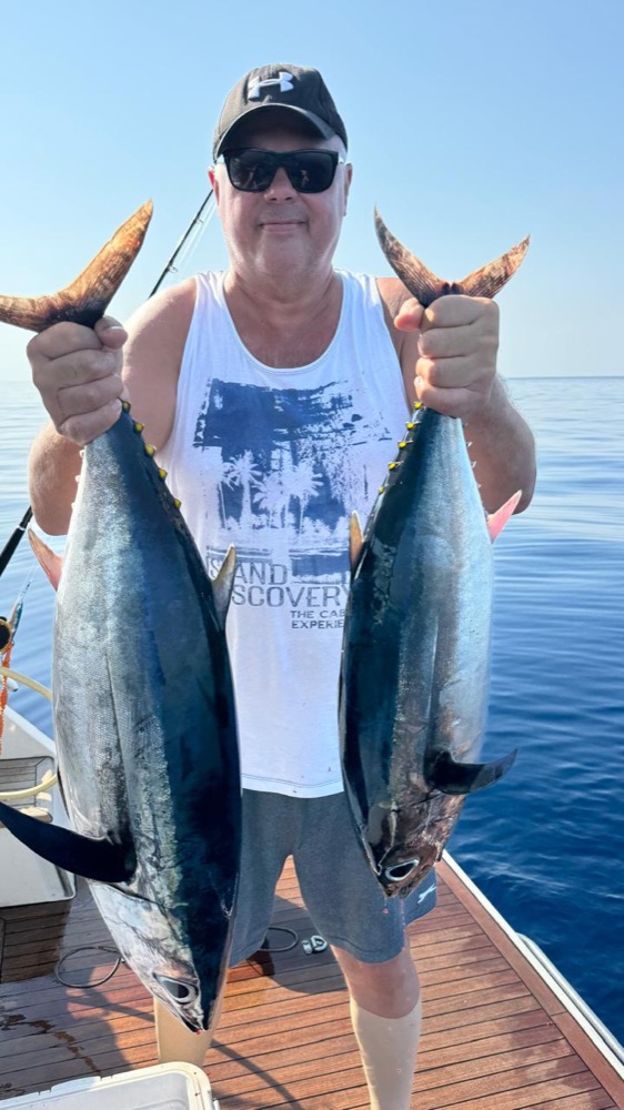Guest holding a large fish on the yacht deck